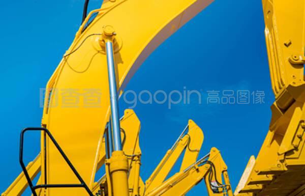 黃色挖土機,液壓活塞臂,對抗晴朗的藍天。建筑工地挖掘用重型機械。液壓機械。大型推土機。重工業